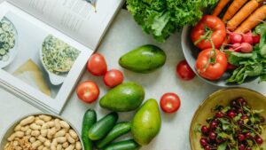 Flat lay shot of vegetables and a cookbook on a white surface.