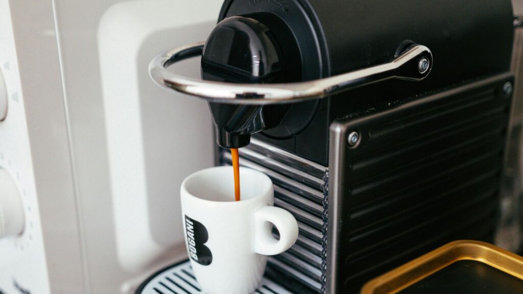 Coffee dripping unto a white cup from a K-Cup Coffee Machine.