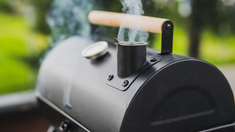 Focus shot on a smoker with steam coming out from it while set outdoors.