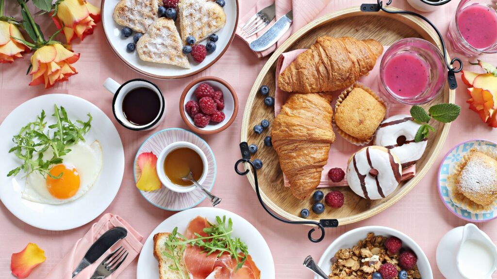 Flat lay shot of a brunch spread on a pink table cloth.