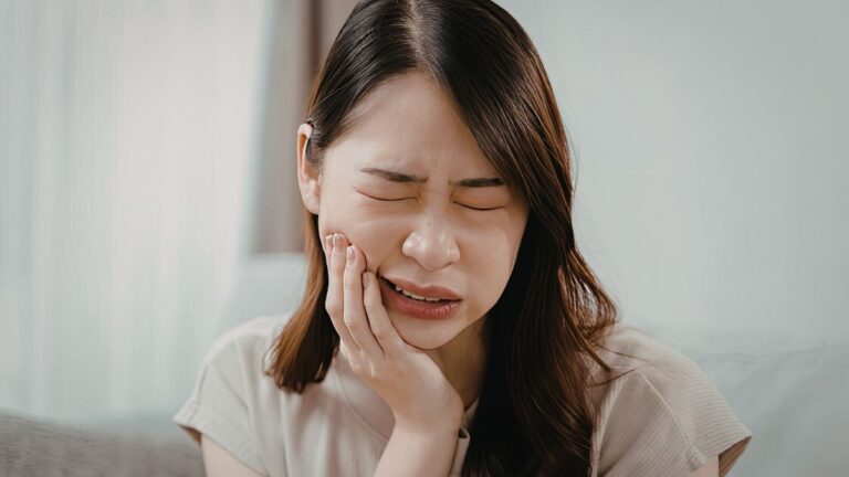 A woman visibly looking like she's in pain, particularly her tooth.