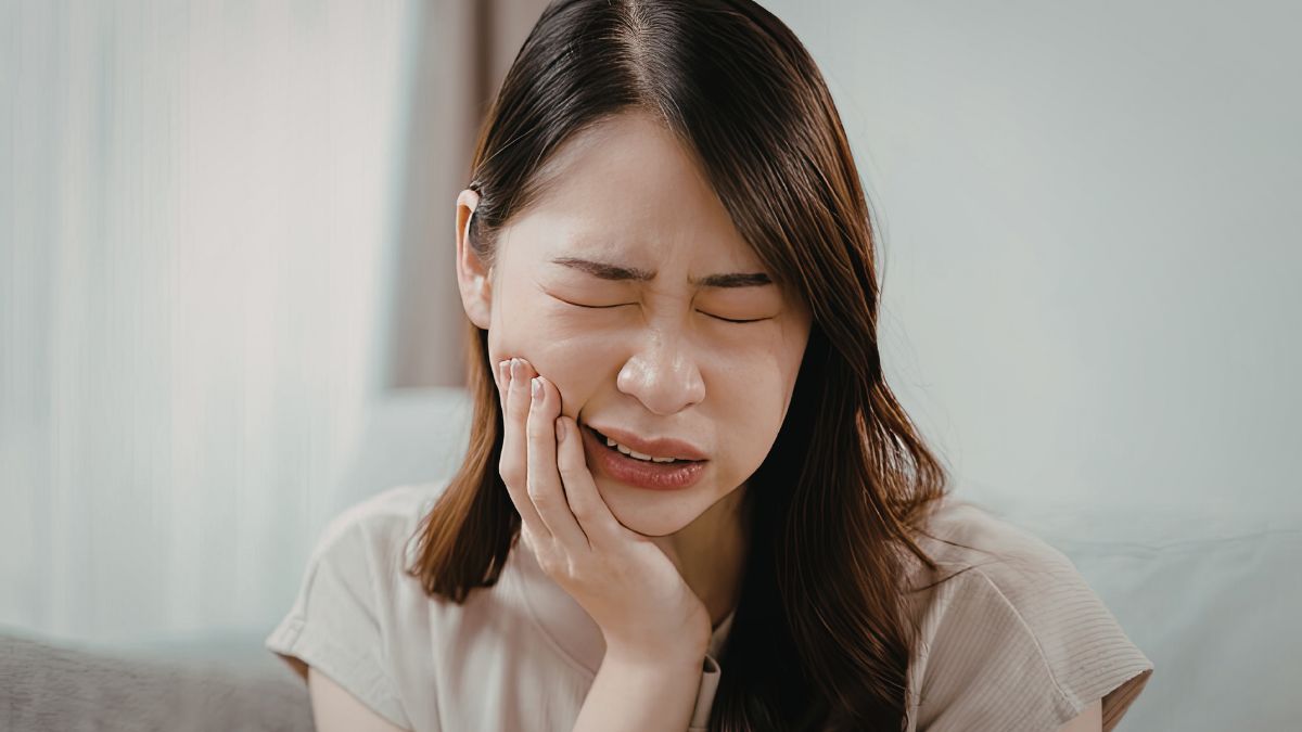 A woman visibly looking like she's in pain, particularly her tooth.