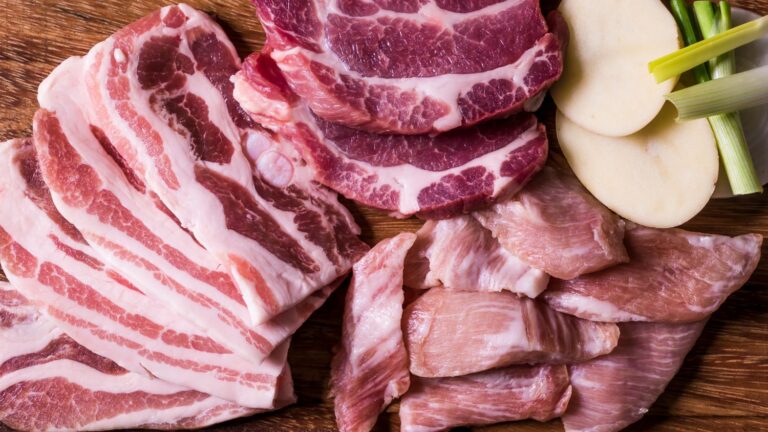 Flat lay shot of raw meat on a wooden surface.