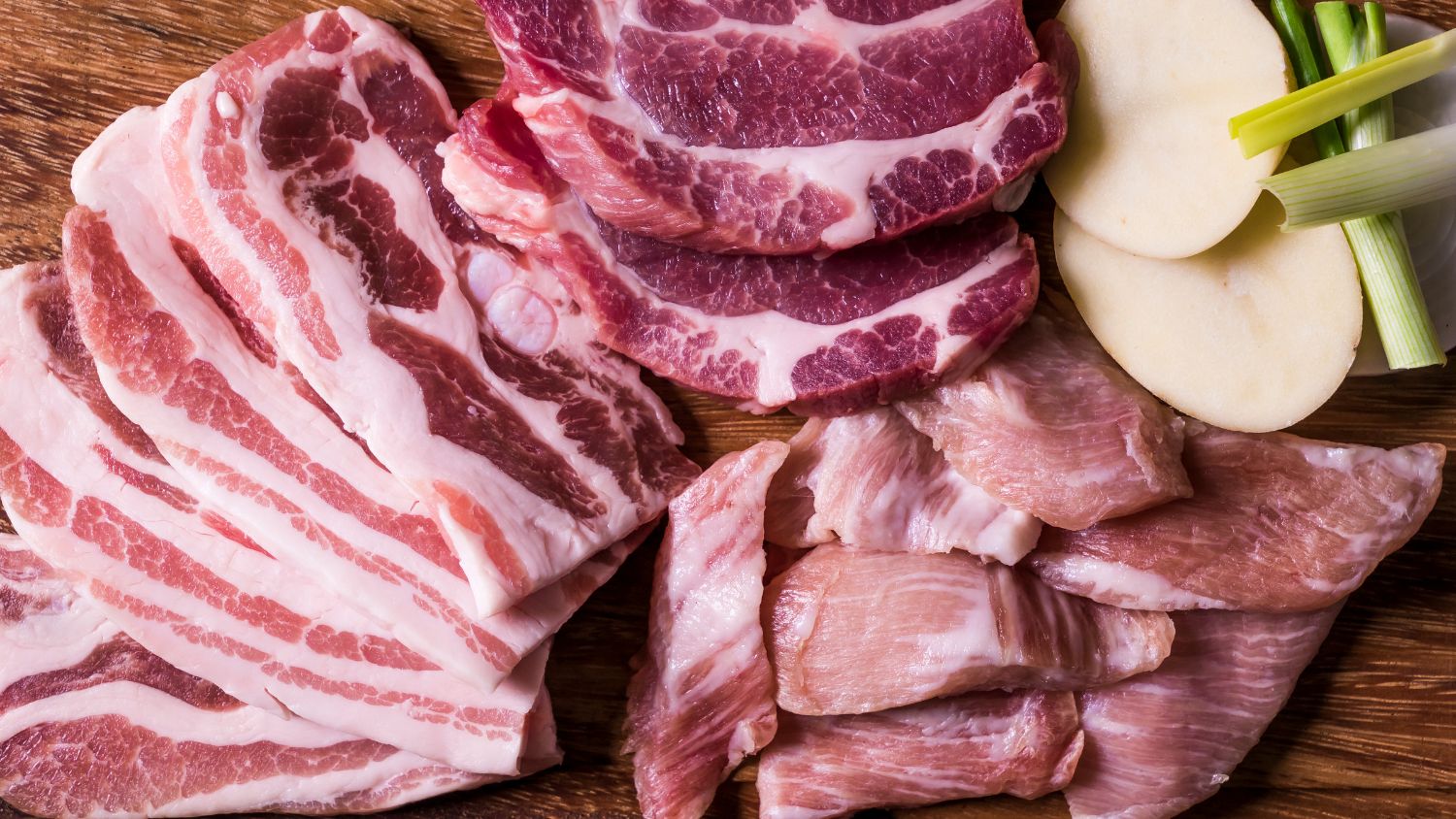 Flat lay shot of raw meat on a wooden surface.
