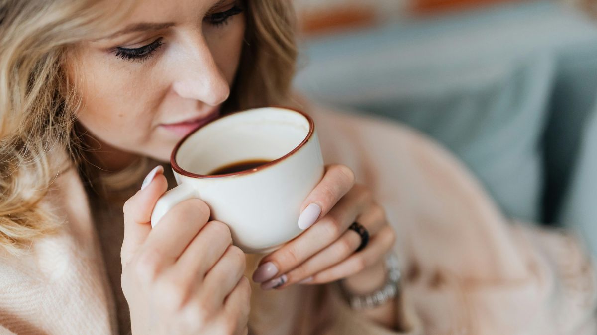 A woman drinking black coffee in a white mug.