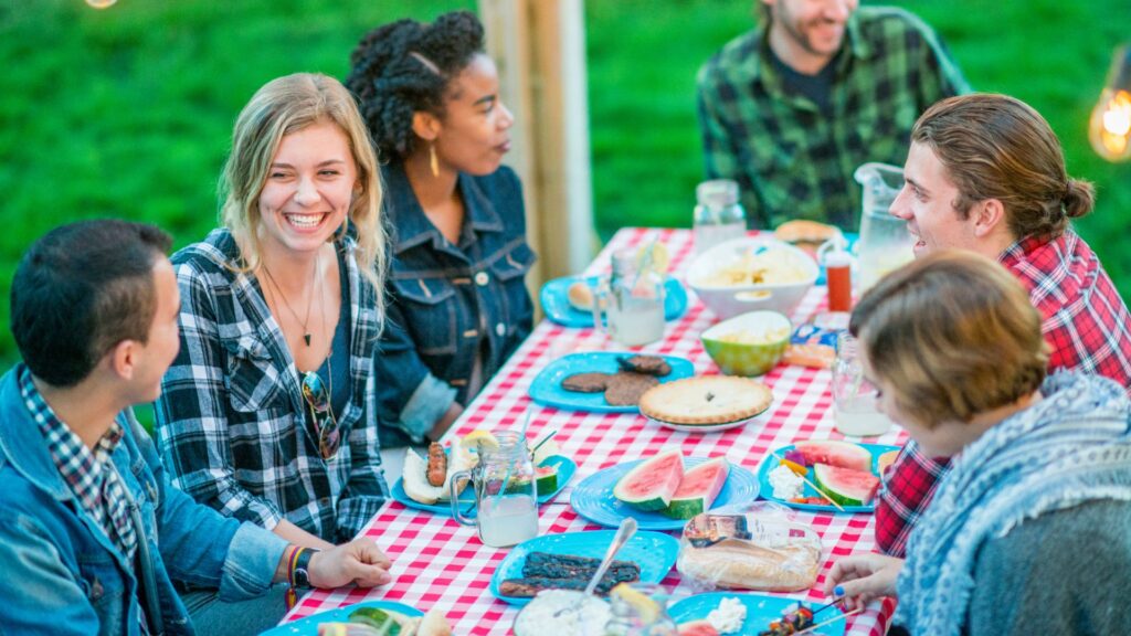 Six people gathered around a table having a simple summer dinner.