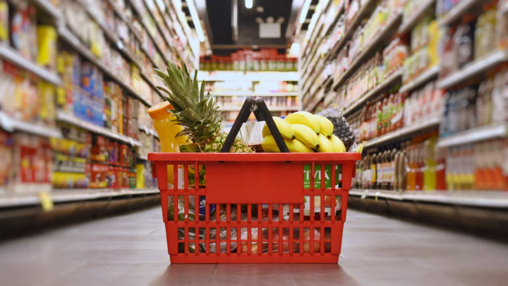 A red basket with grocery items in it.