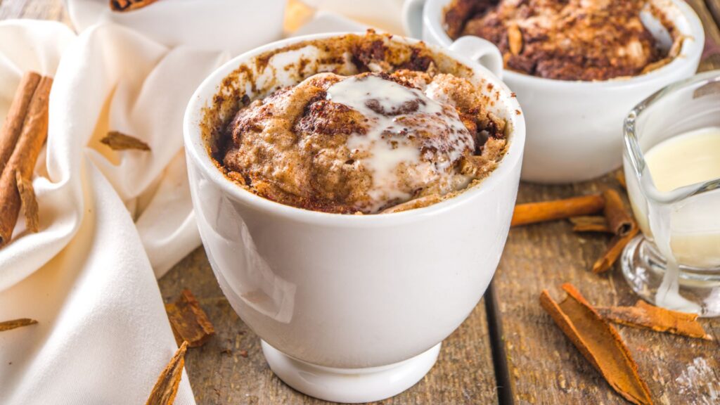 A cinnamon mug cake in a white mug, placed on a wooden surface.