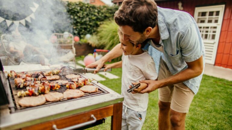 A dad and his son grilling outdoors.