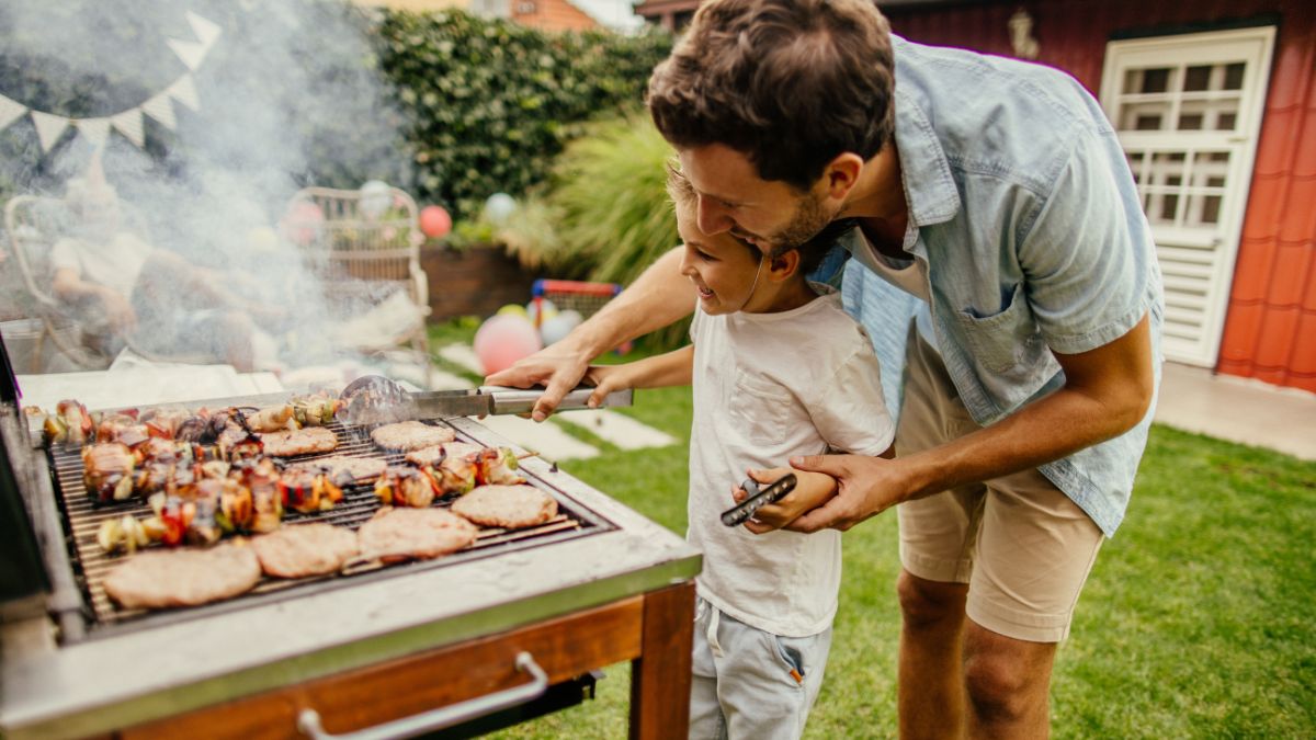 A dad and his son grilling outdoors.