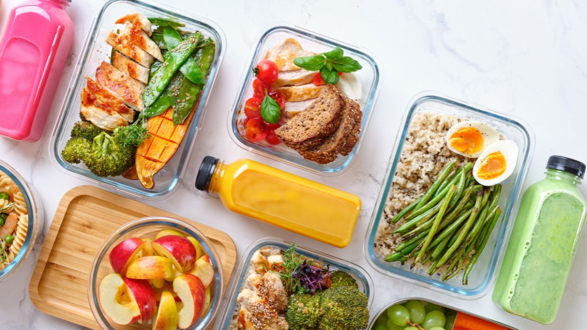 Flat lay shot of glass food containers with an assortment of prepared meals made through meal planning on a budget.