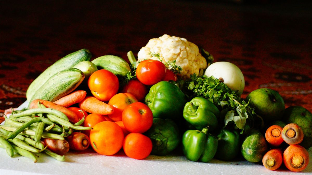 Tomatoes, bell peppers, carrots, cauliflower, and other vegetables piled together on a table.