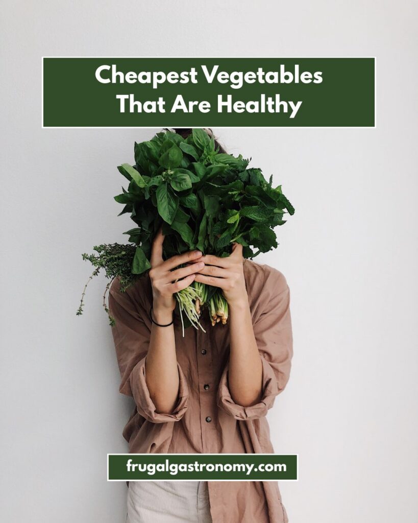 A person holding up a bunch of leafy green vegetables to conceal their face.