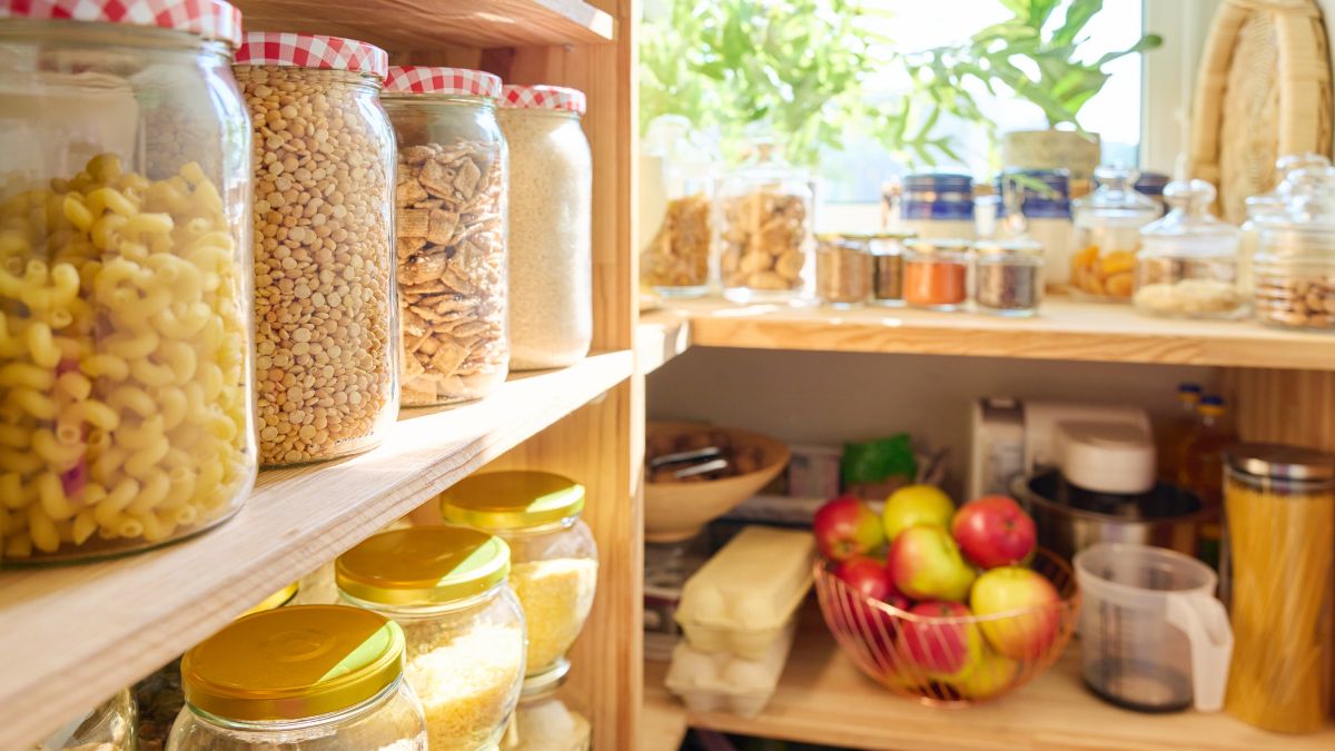 Focus shot on jars of food in a deep pantry with a big window.