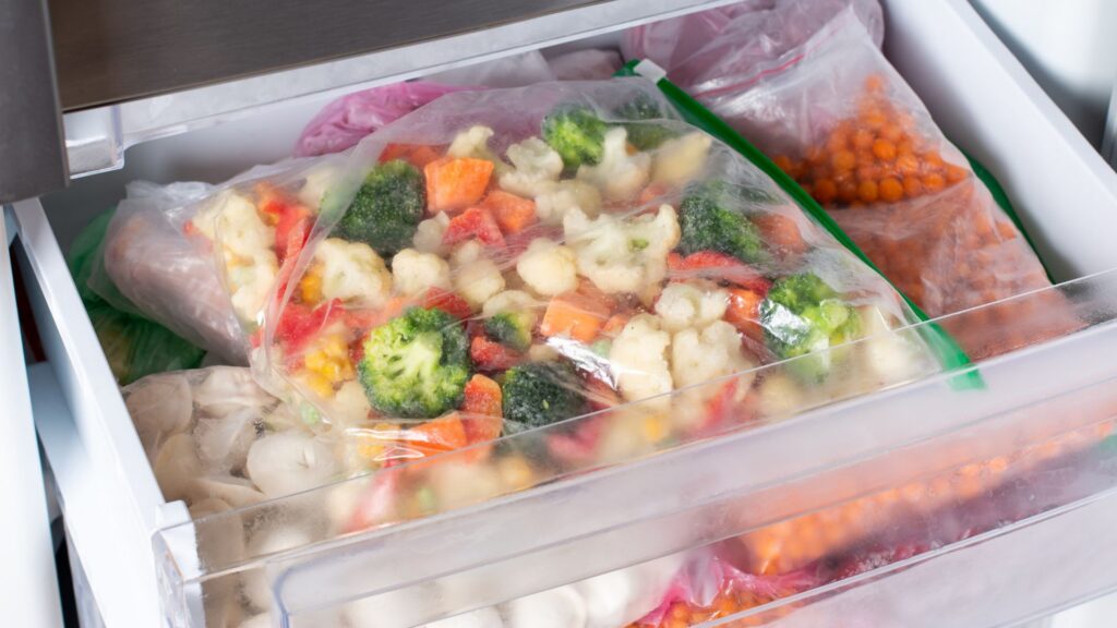 Bags of frozen vegetables in a freezer.
