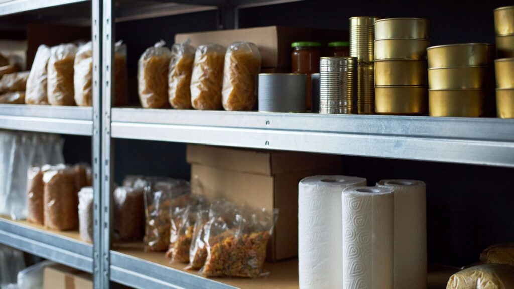 A deep pantry with canned goods, portioned dry goods and rolls of kitchen towels.