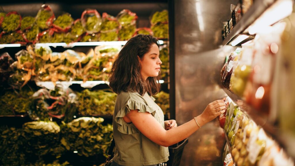 A woman examining a produce in the fresh produce aisle before she buys it.