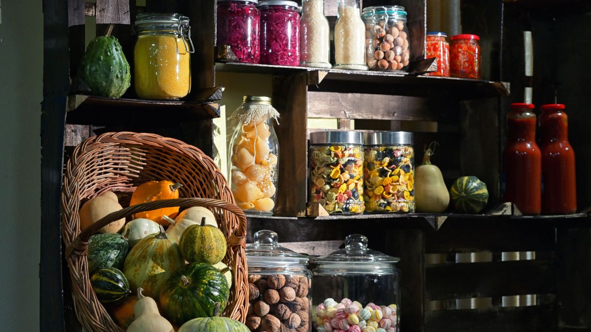 A pantry with dark shelves stocked with fall produce.