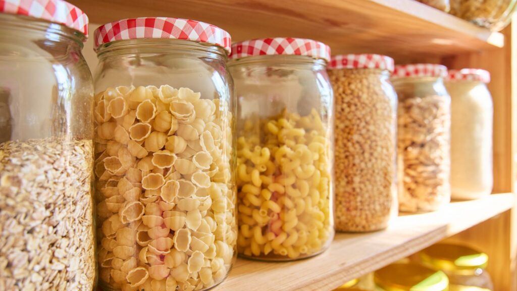 Focus shot on big jars with dry pasta and legumes.