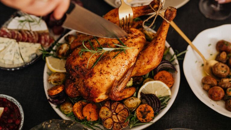 A person carving a rotisserie chicken with a sharp kitchen knife. Here are ways to make the most of a rotisserie chicken.