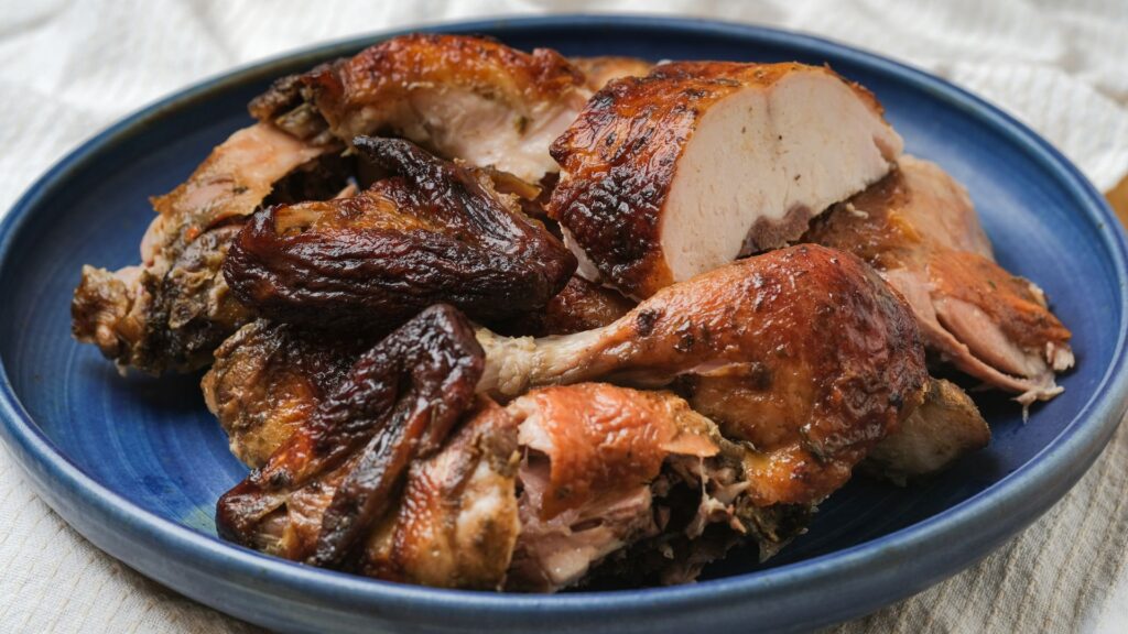 A blue plate with chopped rotisserie chicken, placed on a white placemat.