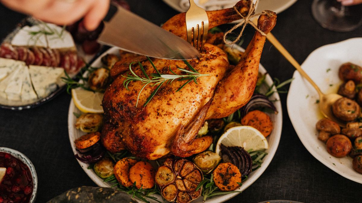 A person carving a rotisserie chicken with a sharp kitchen knife. Here are ways to make the most of a rotisserie chicken.
