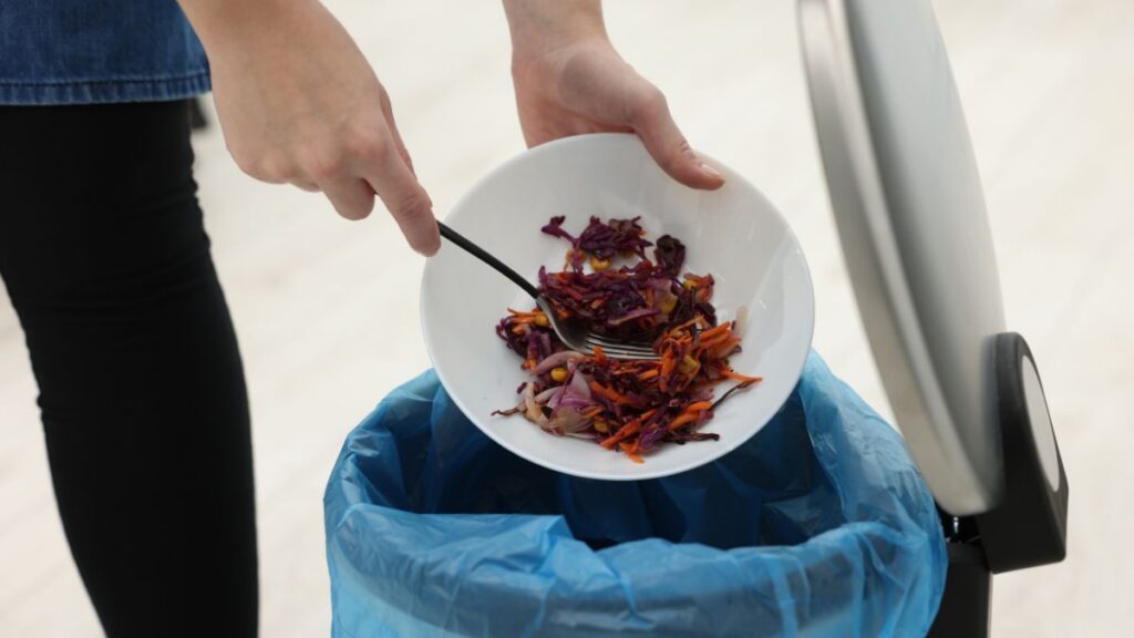 A person throwing away food waste.