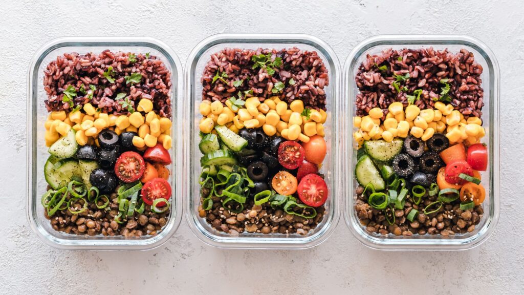 Flat lay shot of 3 prepped meals with grains and vegetables.