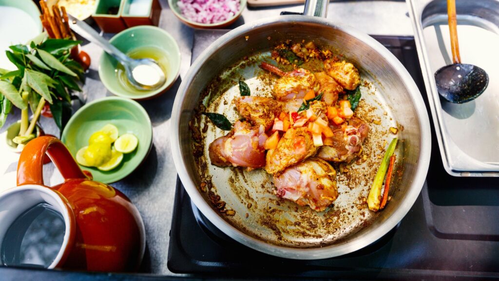 Flat lay shot of a pan with chicken and vegetables cooking in it.