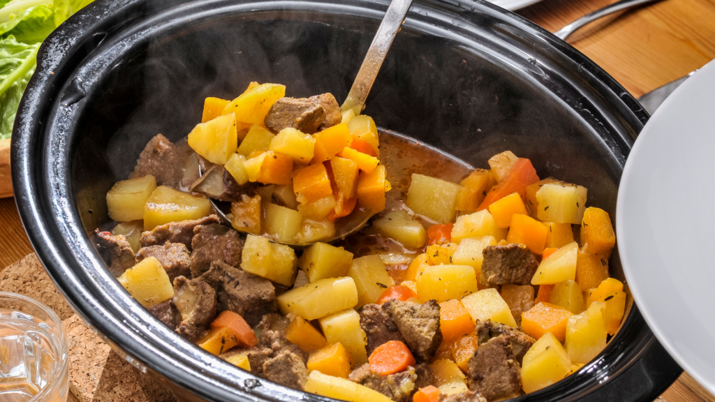 Beef stew being scooped from the slow cooker by a ladle.