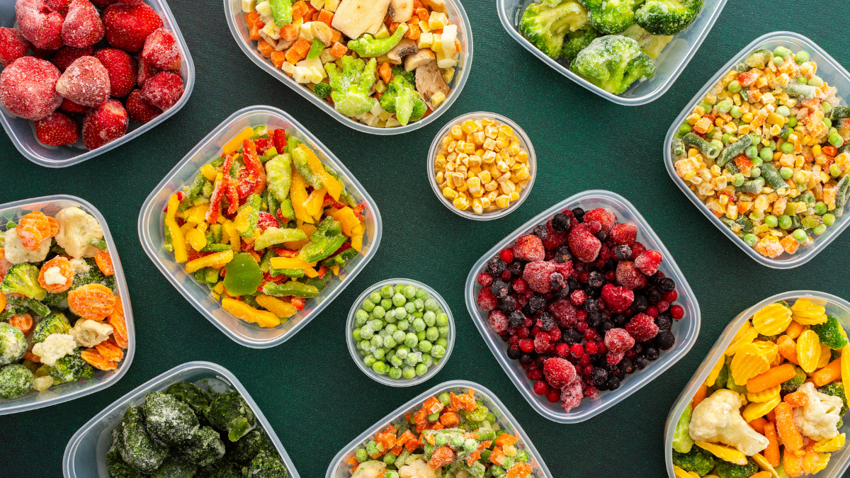 Flat lay shot of an assortment of frozen Fall produce, on an evergreen surface.