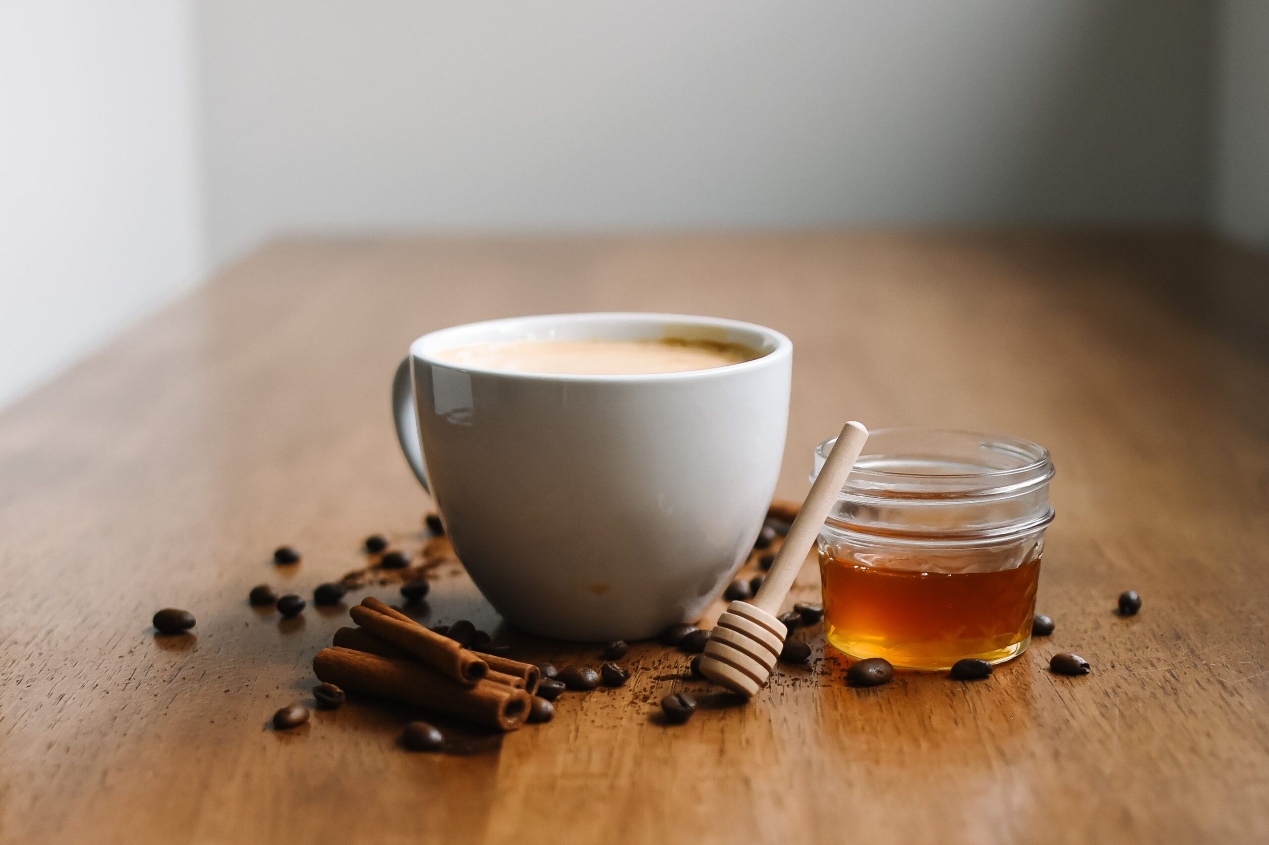 Chai latte made from homemade chai concentrate, in a white cup with cinnamon sticks and honey