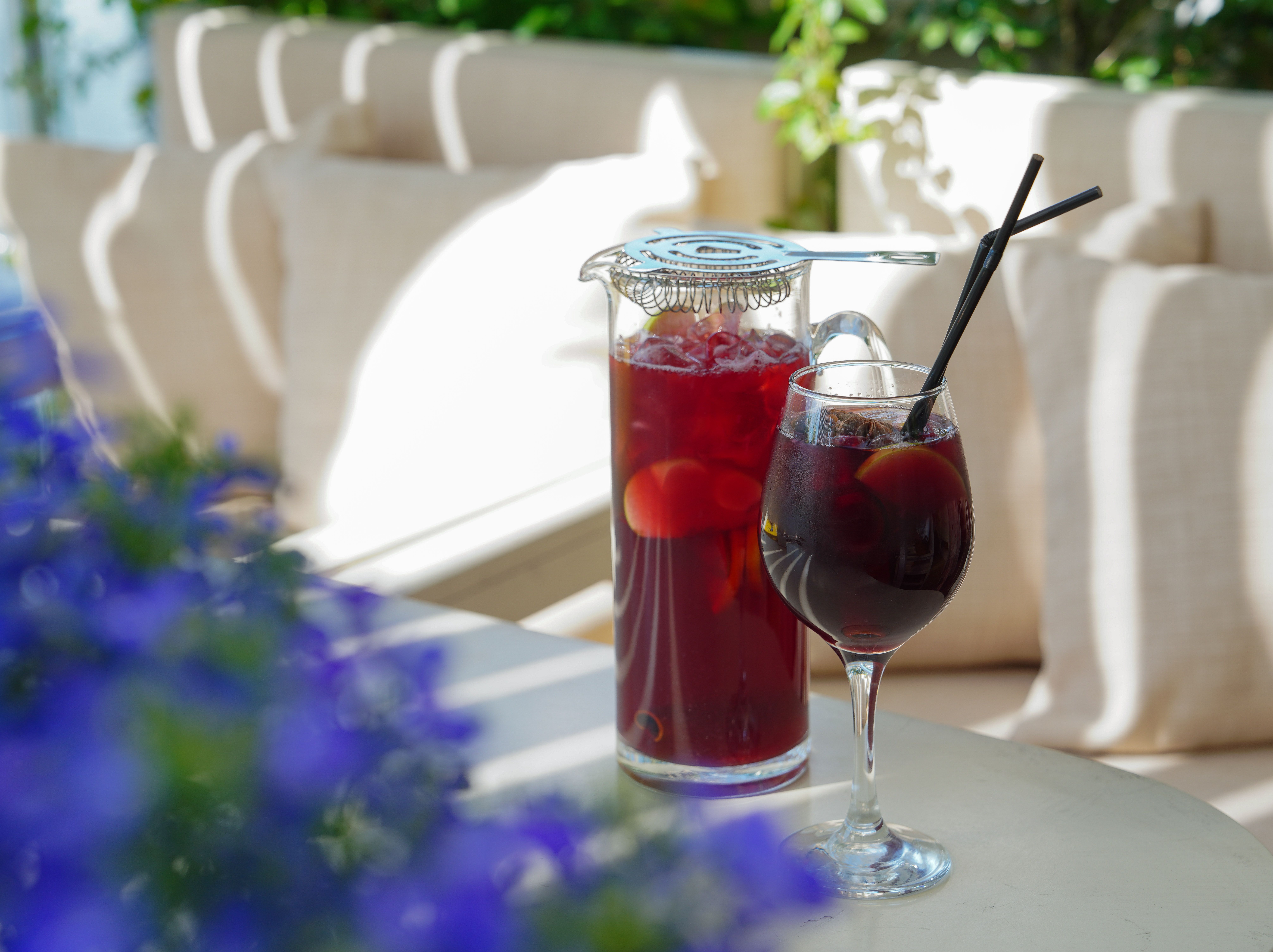 Pitcher and glass of deep red cranberry pear sangria on an outdoor table