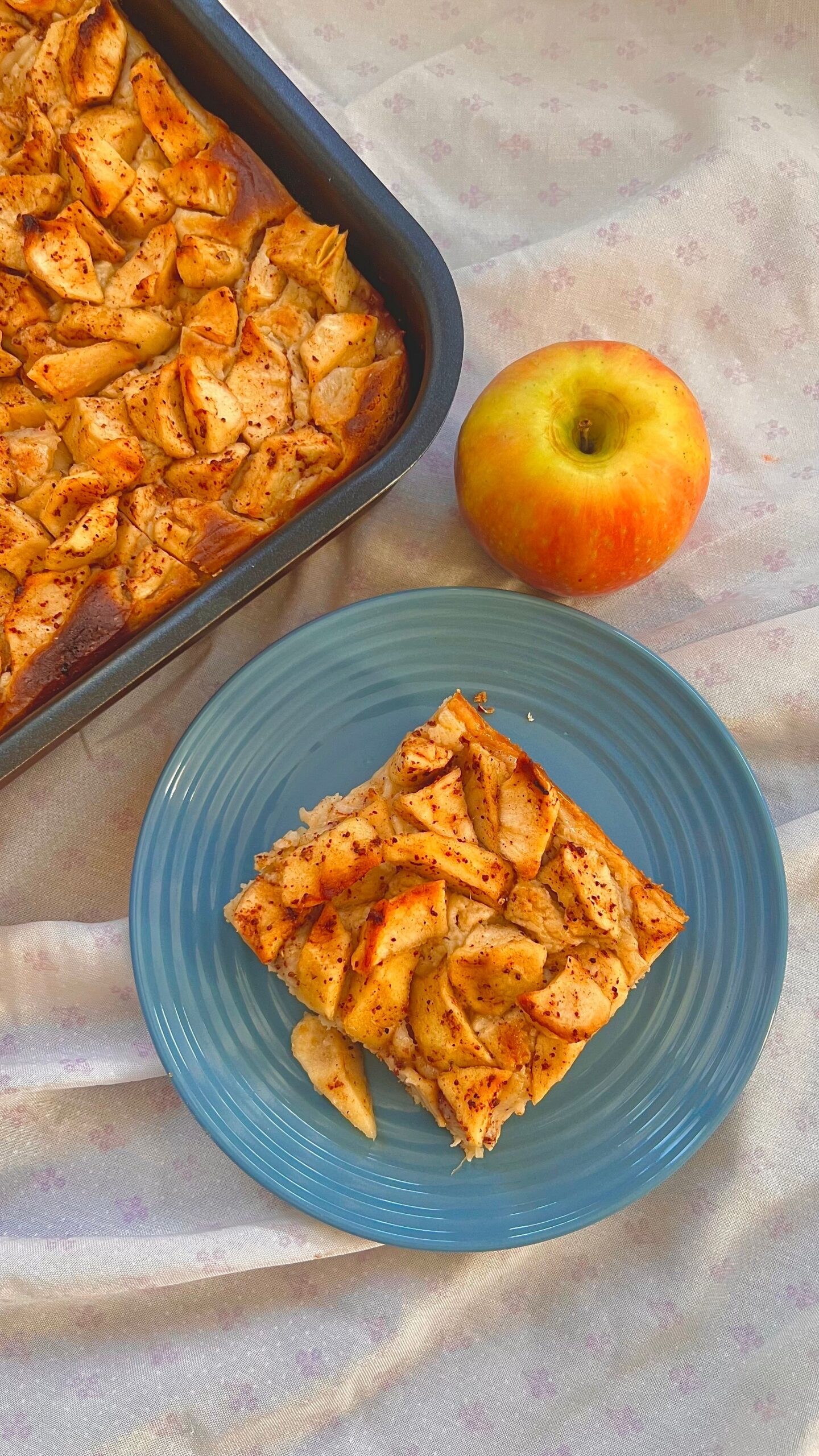 Baking dish of golden baked apple French toast with a whole apple beside it