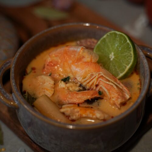 Delicious homemade Thai Tom Yum soup featuring fresh shrimp and tangy lime in a ceramic bowl.