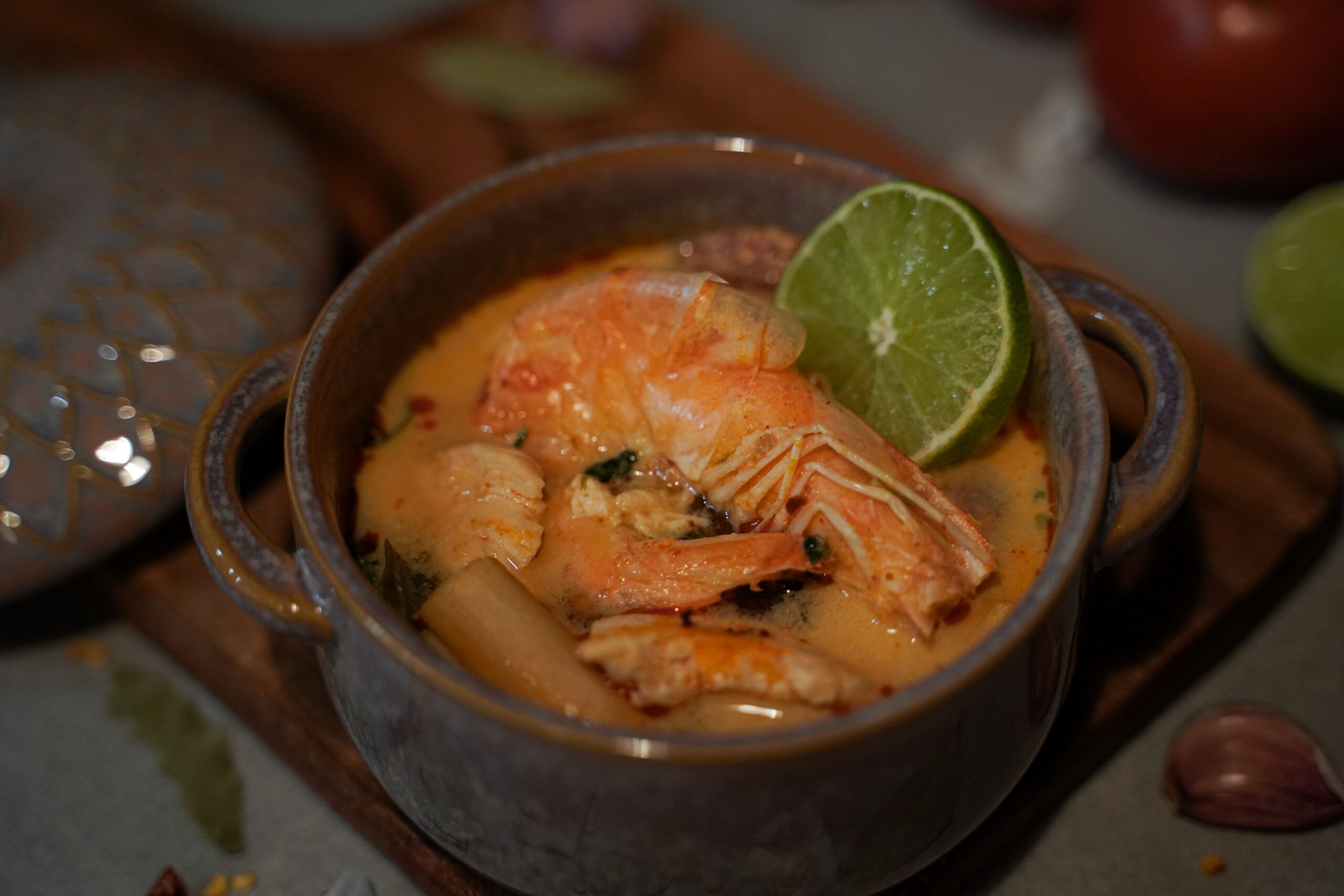 Delicious homemade Thai Tom Yum soup featuring fresh shrimp and tangy lime in a ceramic bowl.