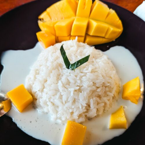 Delicious Thai dessert featuring ripe mango and sticky rice topped with coconut sauce.