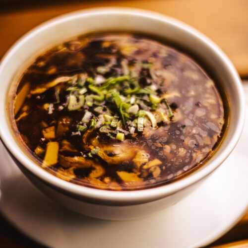 Appetizing hot and sour soup in a bowl garnished with fresh herbs.