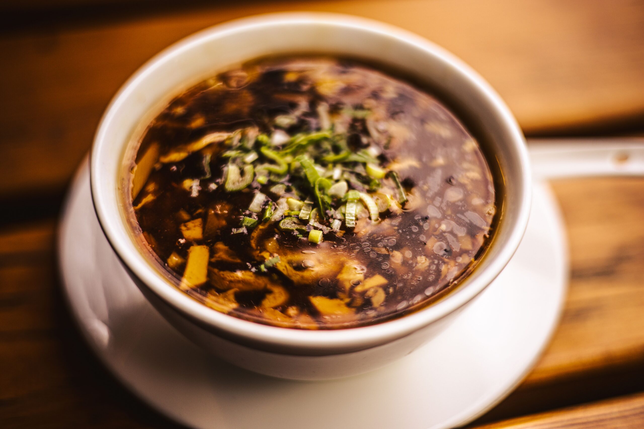 Appetizing hot and sour soup in a bowl garnished with fresh herbs.