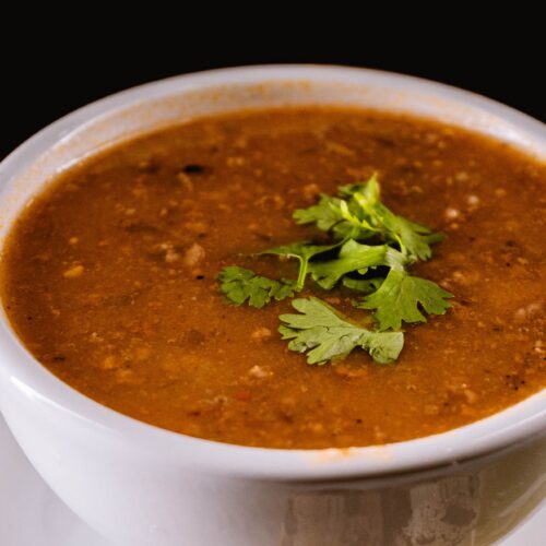 A warm bowl of lentil soup garnished with fresh cilantro.
