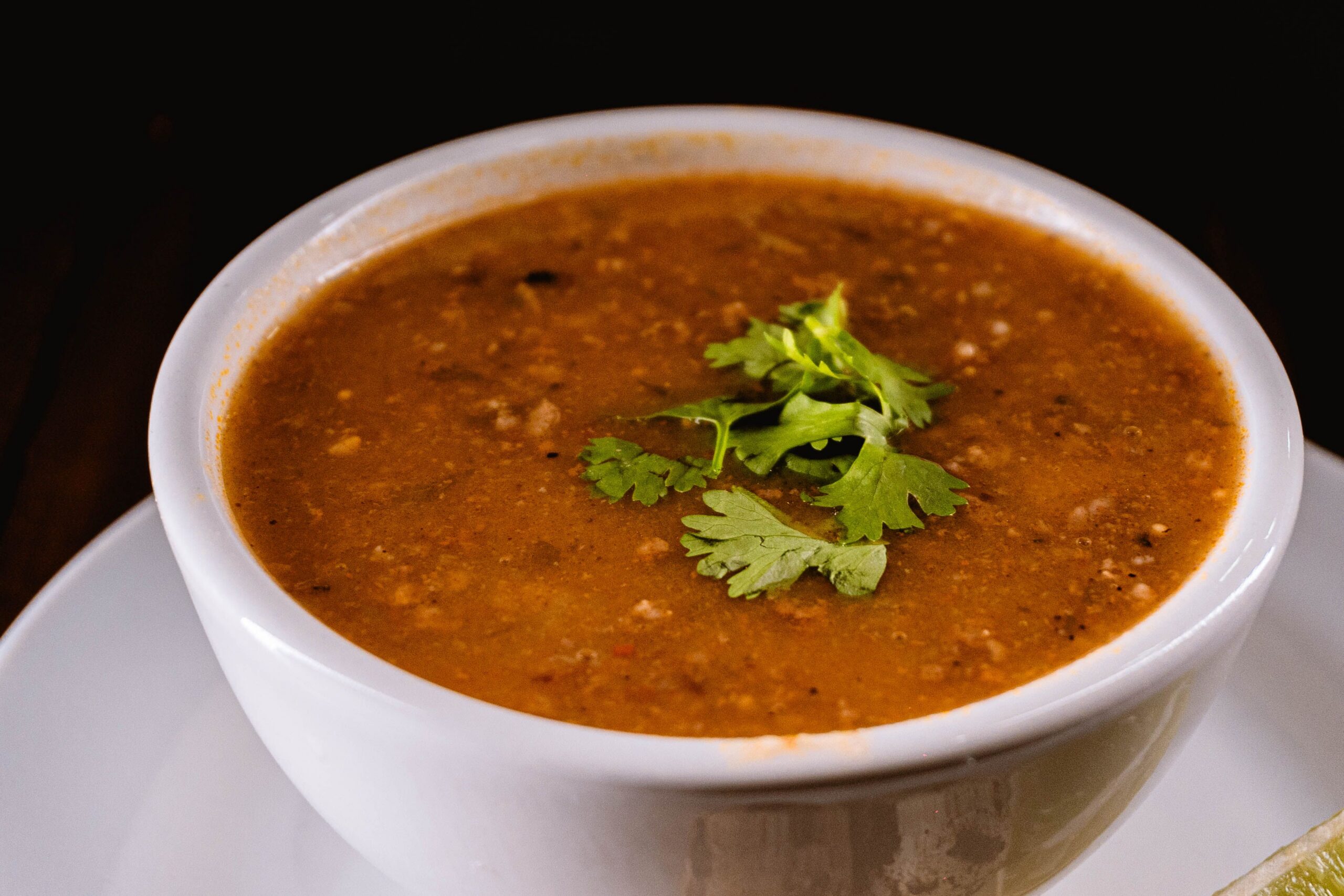 A warm bowl of lentil soup garnished with fresh cilantro.