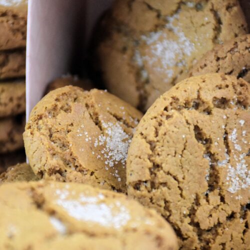 Soft spiced cookies sprinkled with sugar, stacked on a board.
