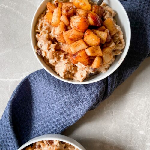 Bowl of creamy oatmeal topped with cinnamon-cooked apple pieces