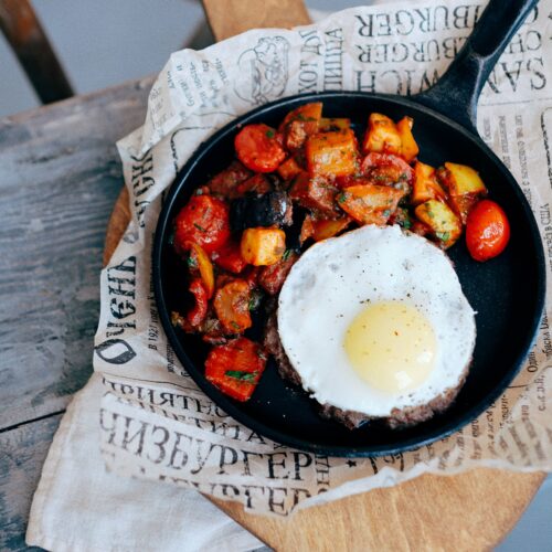 Cast iron skillet of crisp potato hash with a fried egg on top