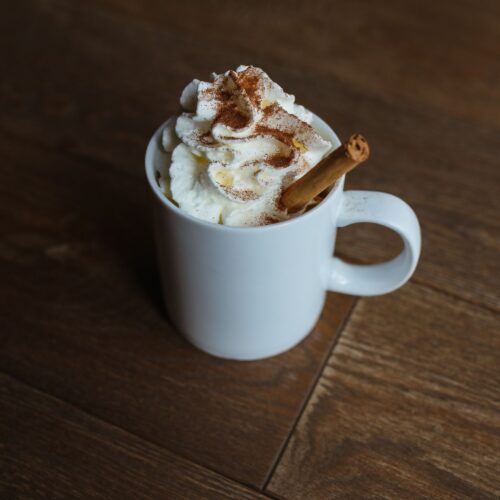 Homemade pumpkin spice latte in a white mug topped with whipped cream and cinnamon