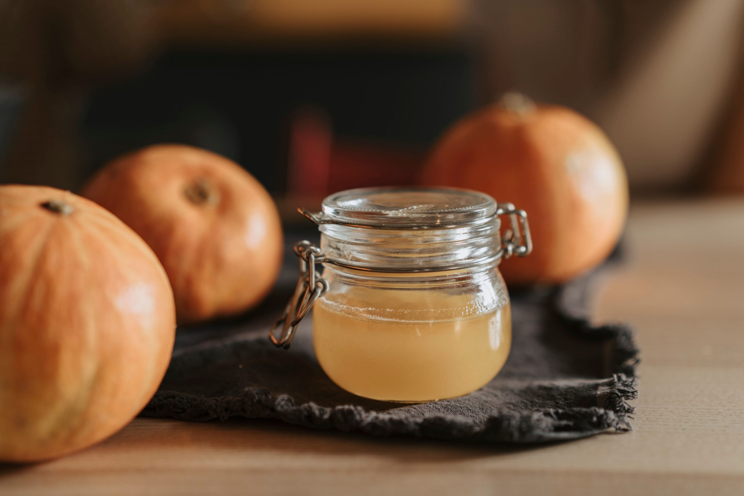Homemade pumpkin spice syrup in a glass jar beside small pumpkins