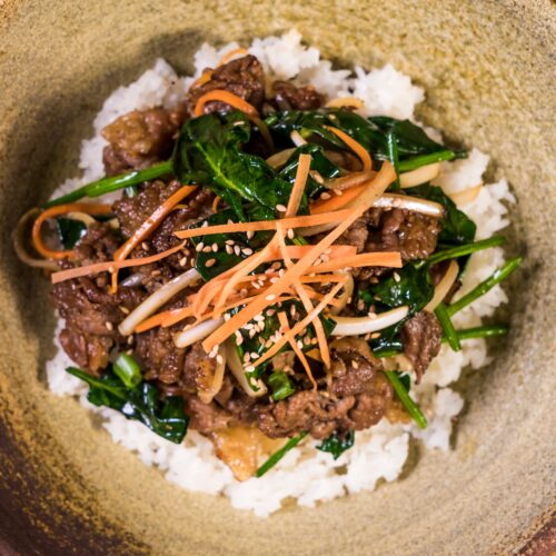 Deliciously vibrant Korean bibimbap topped with marinated bulgogi beef and fresh vegetables.