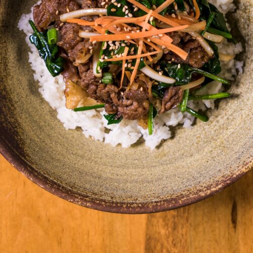 Authentic Korean Bibimbap with fresh vegetables and beef served in a rustic bowl.