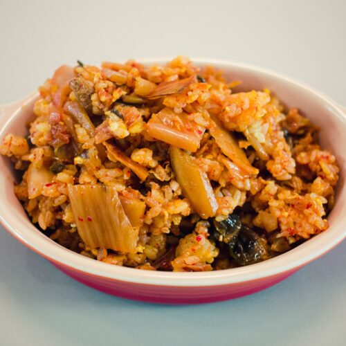Tantalizing Korean Kimchi Fried Rice served in a ceramic bowl, showcasing vibrant colors and textures.