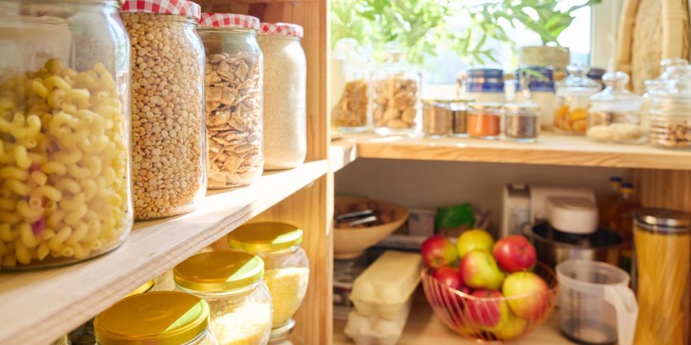 Focus shot on jars of food in a deep pantry with a big window.